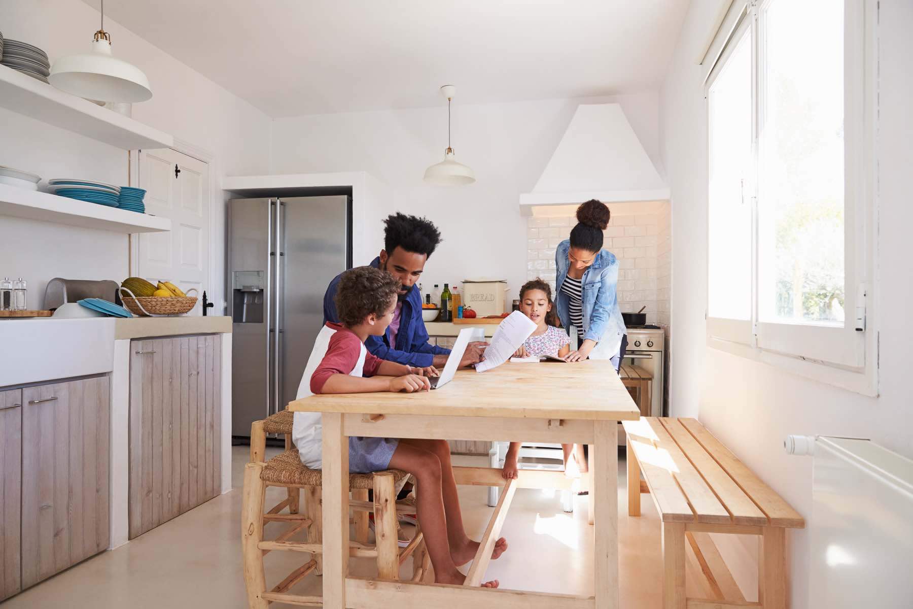 Mom and dad help their kids with homework at kitchen