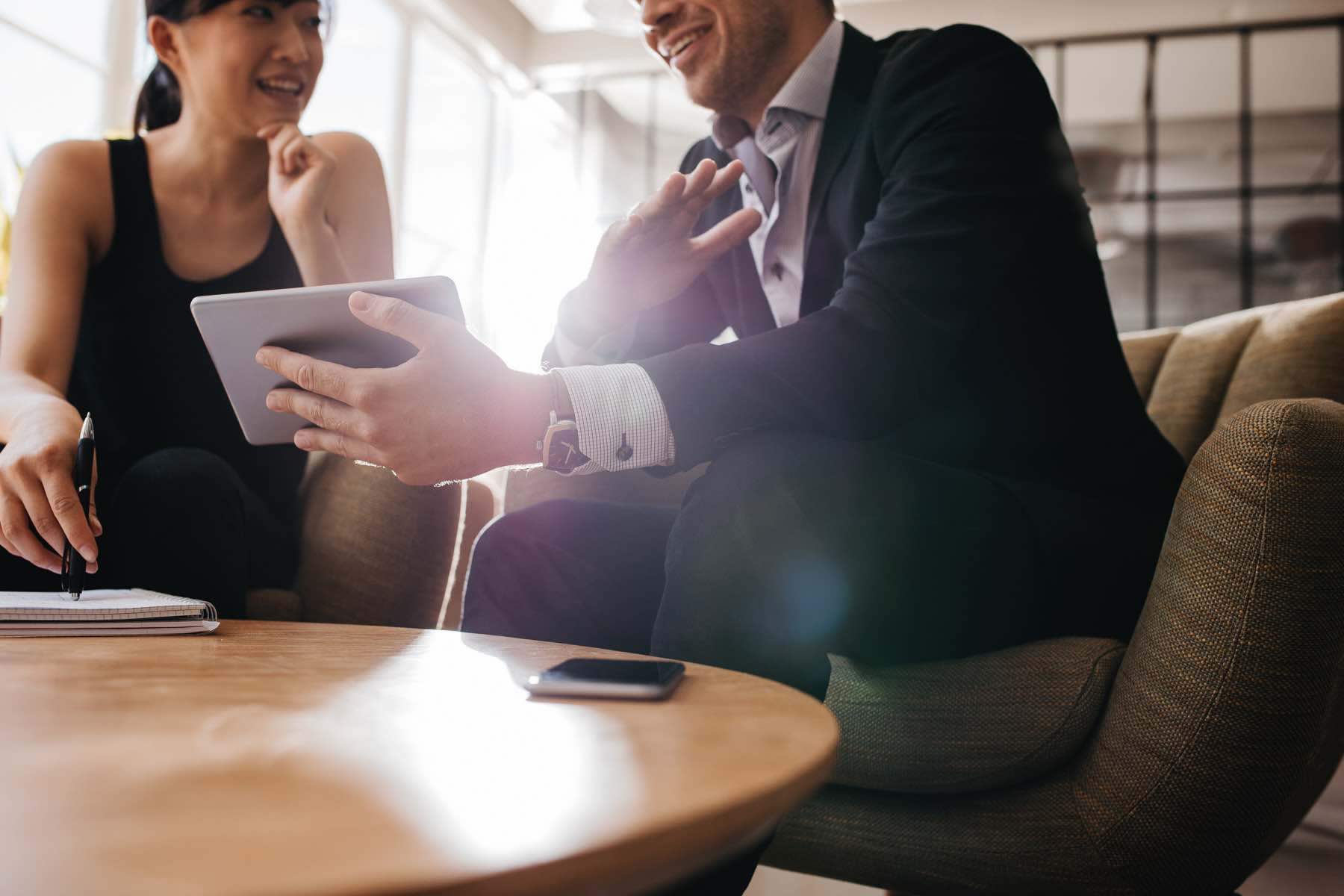 Cropped shot of business professionals having a meeting in office lobby using digital tablet. Business partners using touchscreen computer for project discussion.