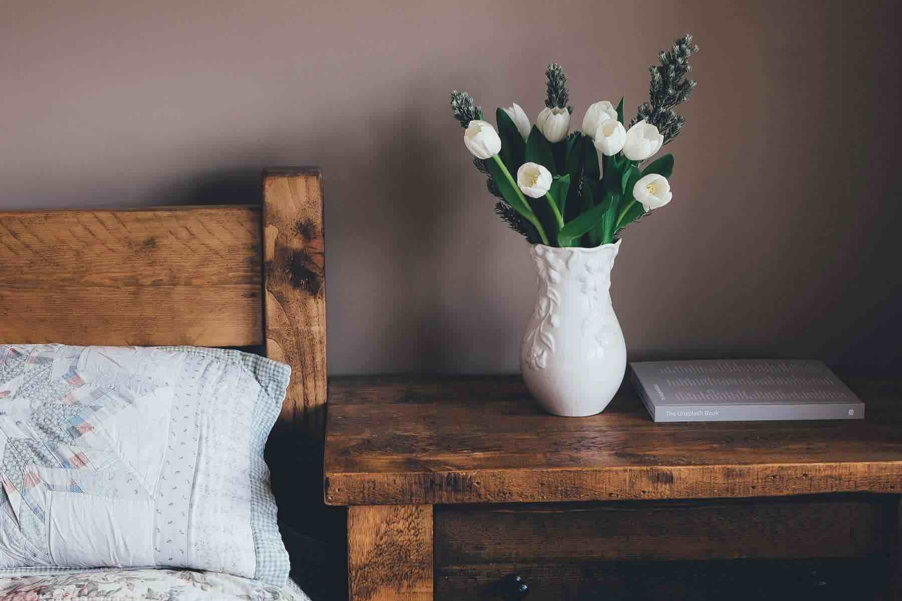 End table in a bedroom with a flower vase