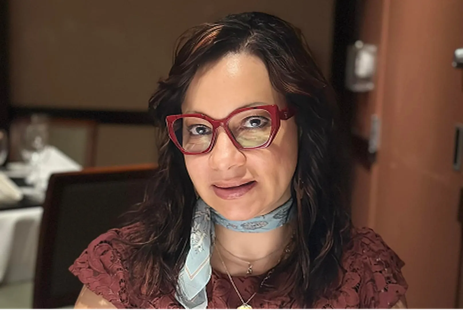 Abby Guadalupe, a Mortgage Loan Officer, at home wearing red-framed glasses.