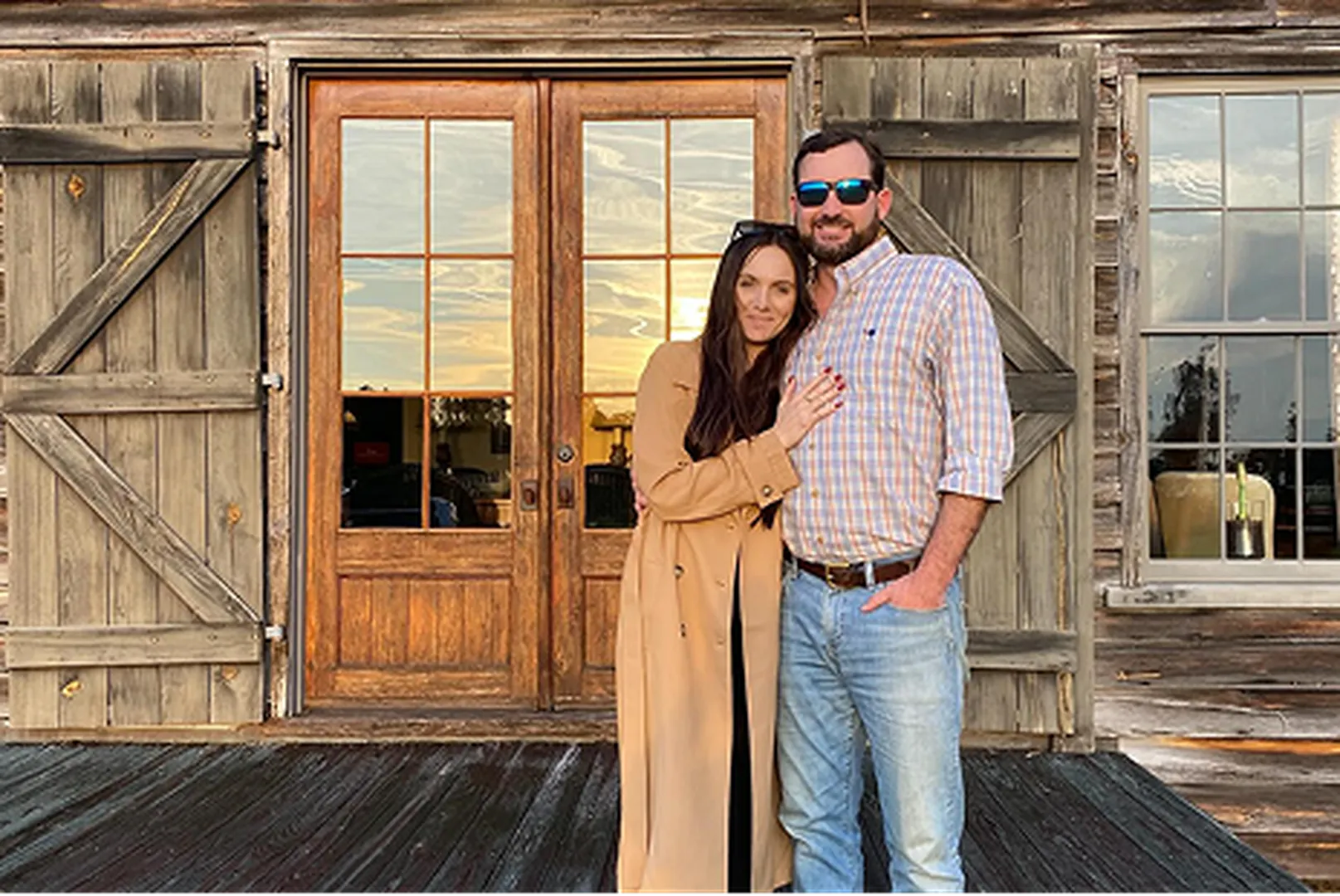 James Burton, Branch Manager, with his wife in front of a wooden house.