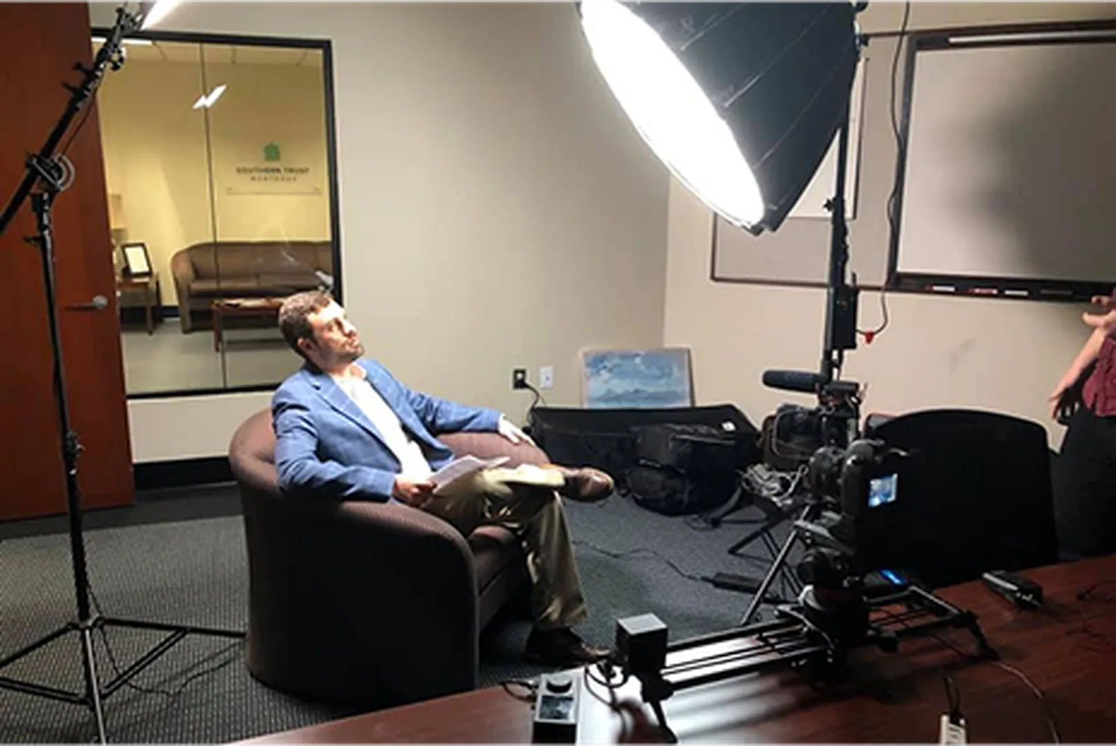 Mark Atkinson, Mortgage Loan Officer, sitting on a couch in a studio.